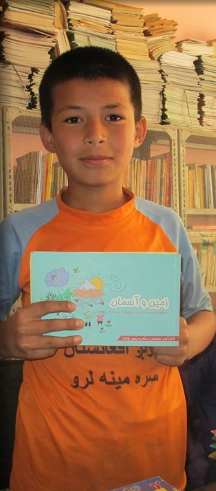 A boy holding an ABLE storybook in a library
